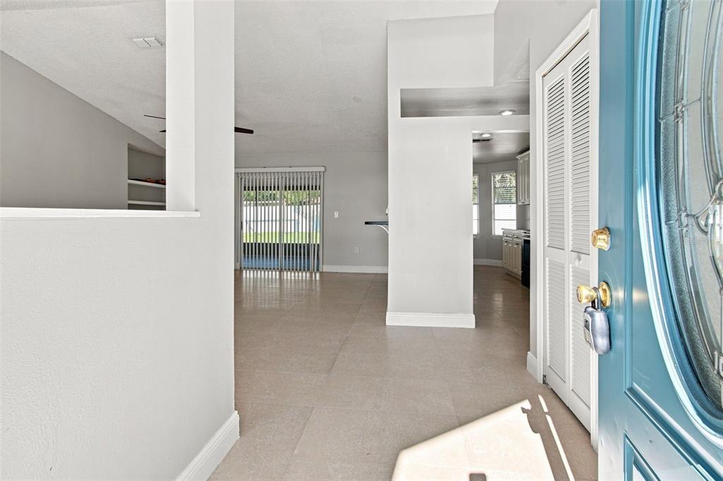 An entryway with light tile flooring leads into a living area with sliding glass doors — 4745 CANTERBURY DRIVE, LAND O LAKES, FL