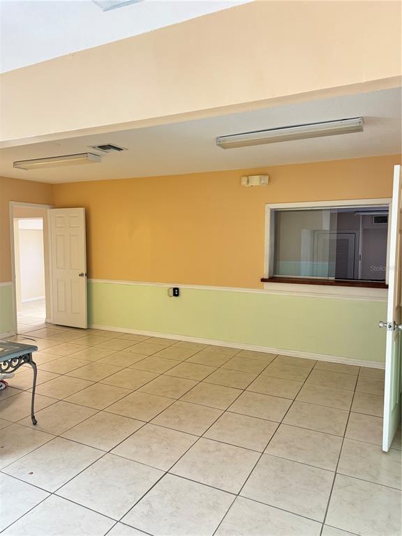 An interior room features light-colored tile flooring, two-tone walls, a window, and two doorways — 706 N 7TH STREET, FORT PIERCE, FL