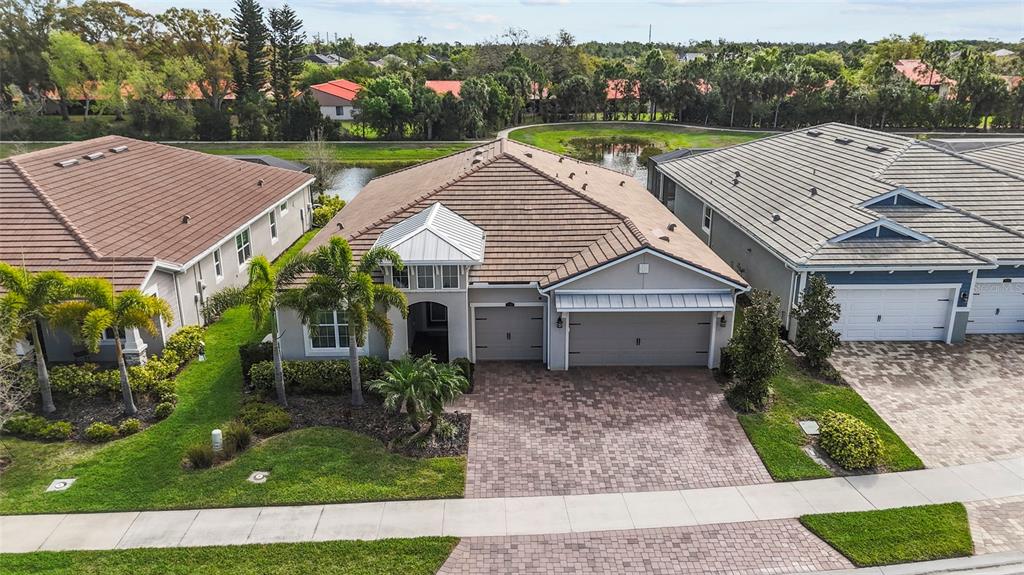 An aerial view shows a single-story house with a tiled roof and a paved driveway — 5745 LONG SHORE LOOP, SARASOTA, FL