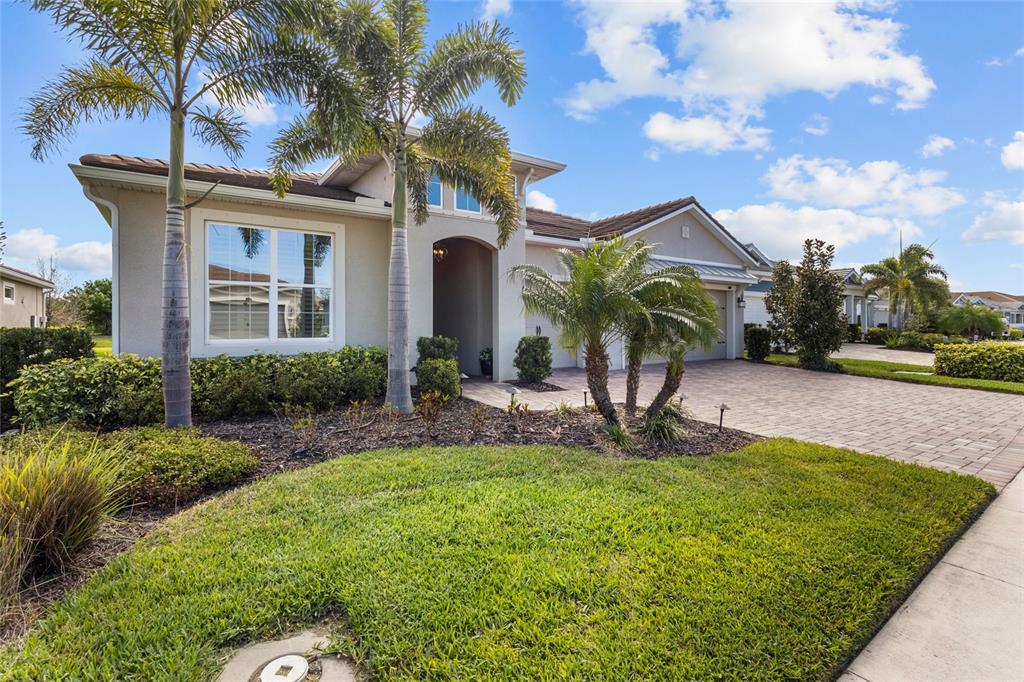 A single-story house with a paved driveway, palm trees, and a landscaped front yard — 5745 LONG SHORE LOOP, SARASOTA, FL