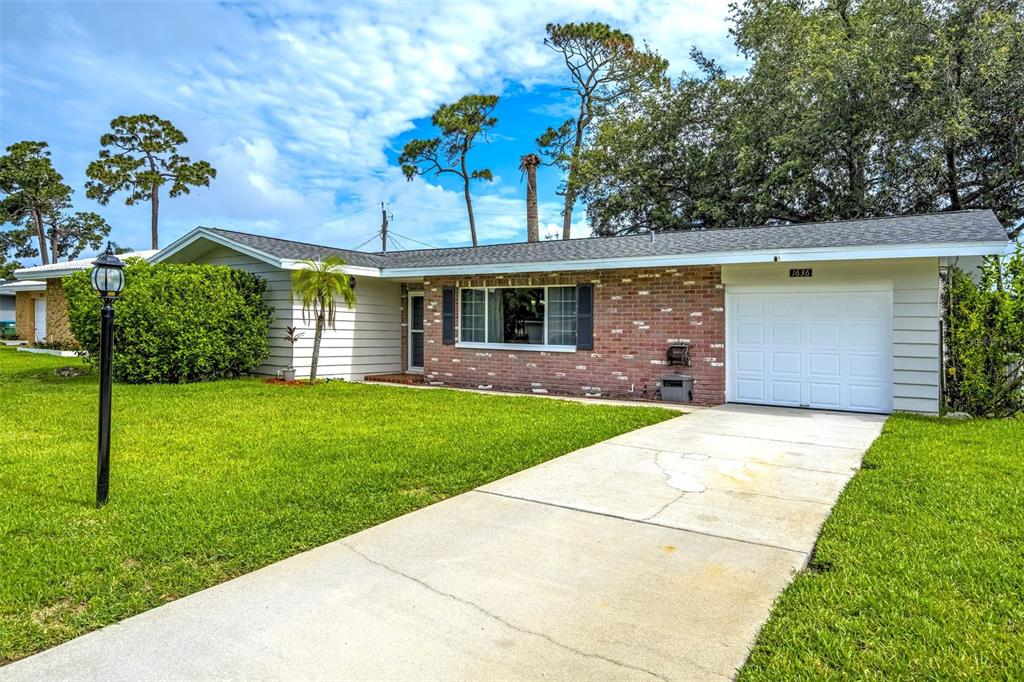 A backyard features a stone patio, outdoor dining set, and a house with a sunroom — 1636 LEISURE DRIVE, CLEARWATER, FL