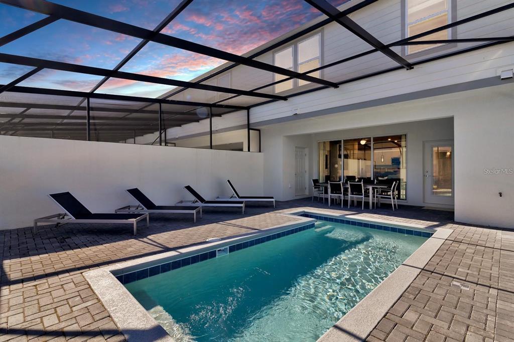 A screened-in patio features a rectangular swimming pool, lounge chairs, and an outdoor dining area — 108 JETTY WAY, DAVENPORT, FL