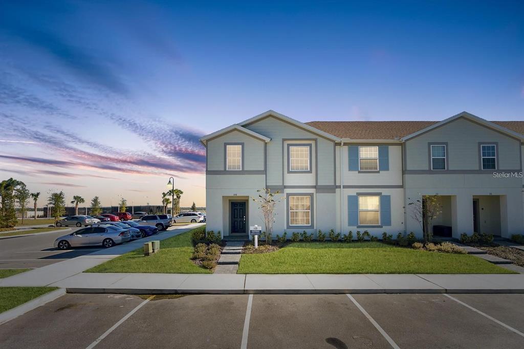 A two-story townhouse exterior with light siding, blue shutters, and a paved parking lot — 108 JETTY WAY, DAVENPORT, FL