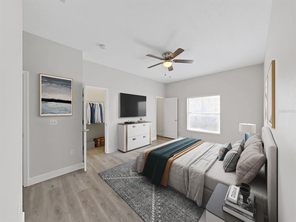 A bedroom with light gray walls, wood-look flooring, a ceiling fan, and a queen-sized bed — 11908 FERN BLOSSOM DRIVE, GIBSONTON, FL
