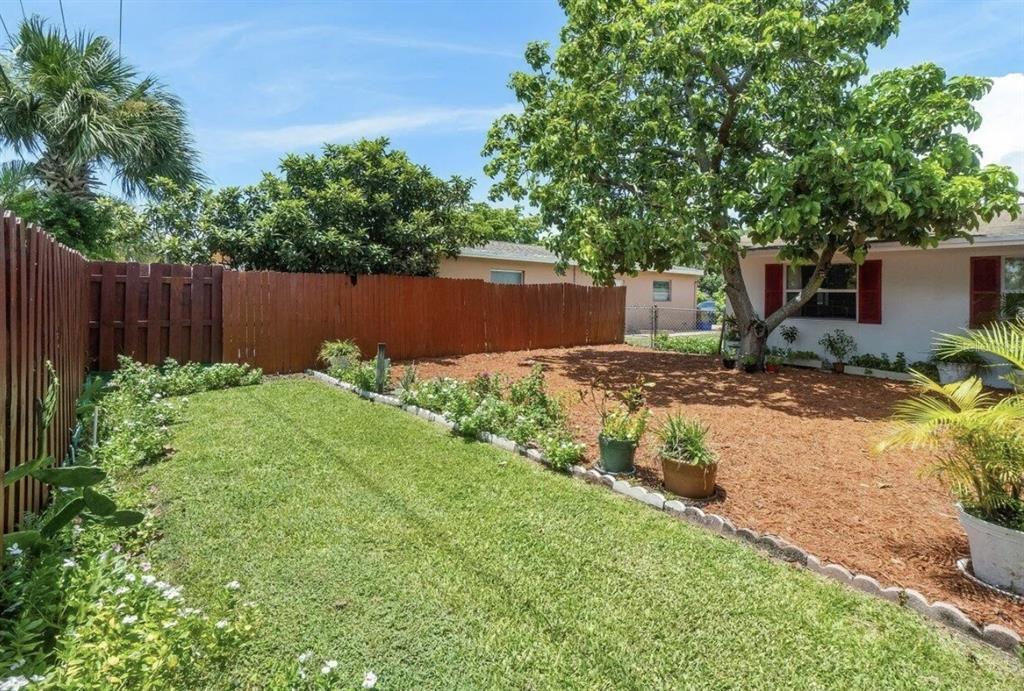 A backyard features a grassy lawn, a mulched area with a tree, and wooden fencing — 717 LINDELL BOULEVARD, DELRAY BEACH, FL