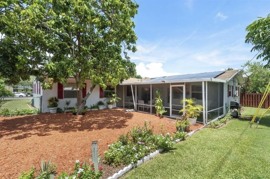 The backyard features a screened-in patio, a large tree, and a mulch-covered garden area — 717 LINDELL BOULEVARD, DELRAY BEACH, FL
