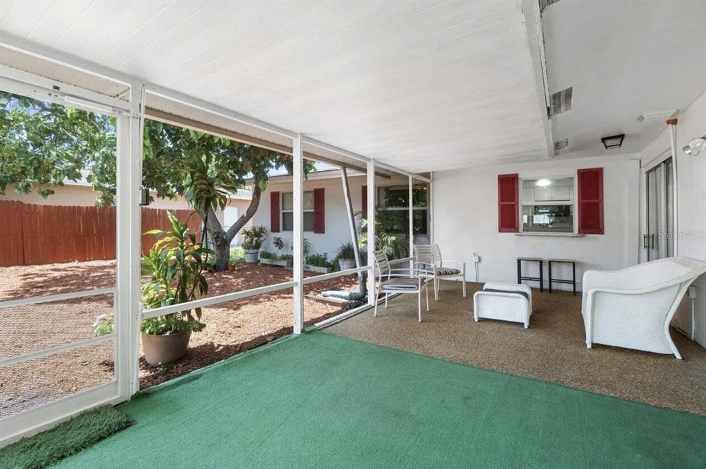 A screened-in patio with green carpeting, outdoor furniture, and a view of the backyard — 717 LINDELL BOULEVARD, DELRAY BEACH, FL