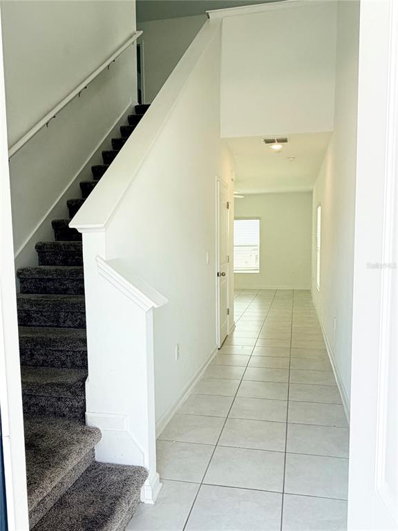 A carpeted staircase leads to an upper level next to a tiled hallway — 2847 BIG SUR ROAD, DAVENPORT, FL