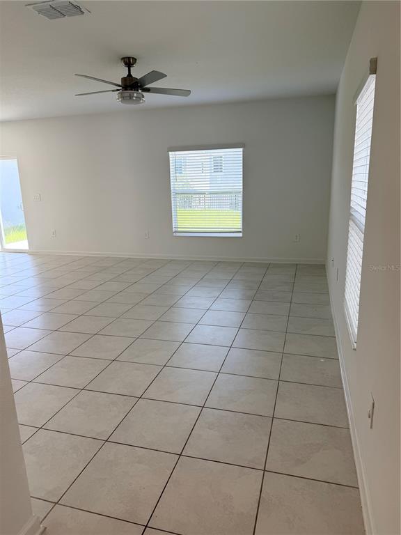 An empty room with light-colored tile flooring, a ceiling fan, and two windows — 2847 BIG SUR ROAD, DAVENPORT, FL