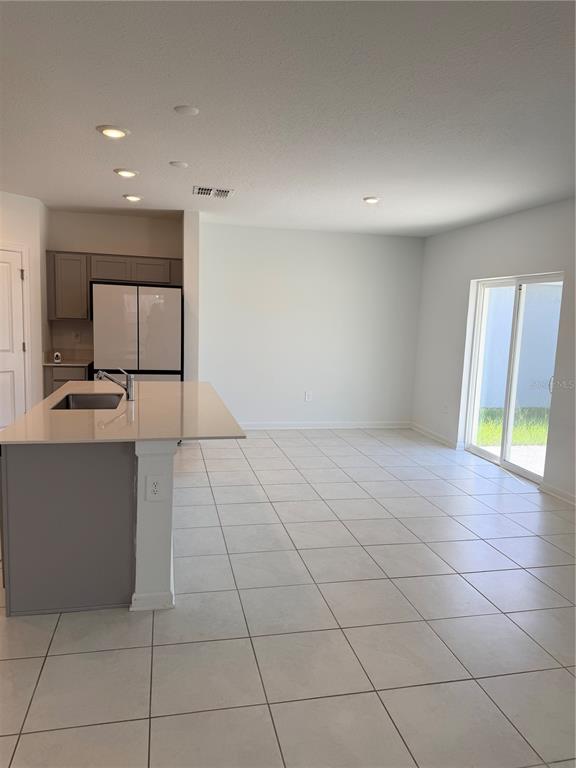 A kitchen with a large island, stainless steel appliances, and tile flooring leads to sliding doors — 2847 BIG SUR ROAD, DAVENPORT, FL