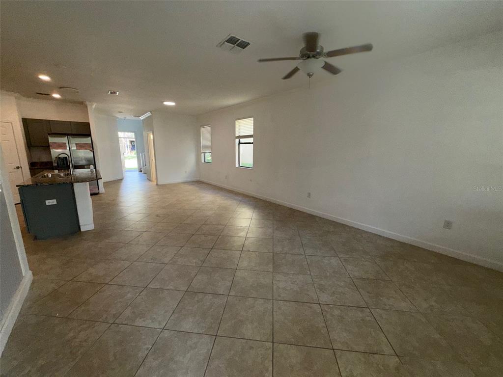 An open-concept living area features tile flooring, a ceiling fan, and an adjacent kitchen — 950 TERRA VISTA STREET, BRANDON, FL