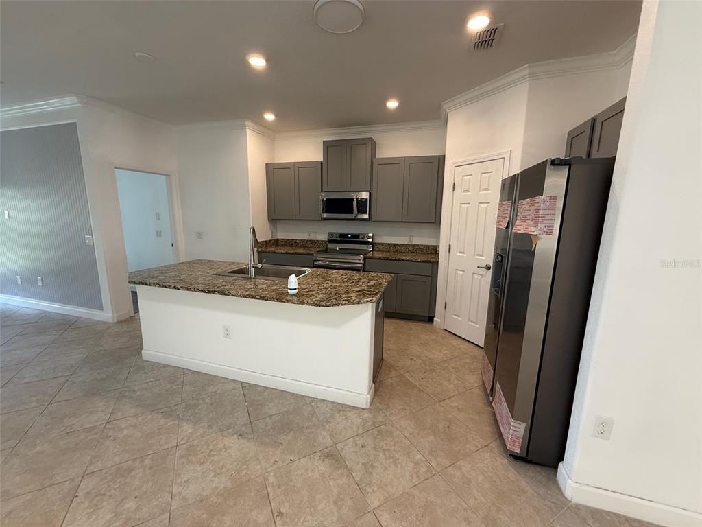 A kitchen features gray cabinetry, granite countertops, a center island, and stainless steel appliances — 950 TERRA VISTA STREET, BRANDON, FL