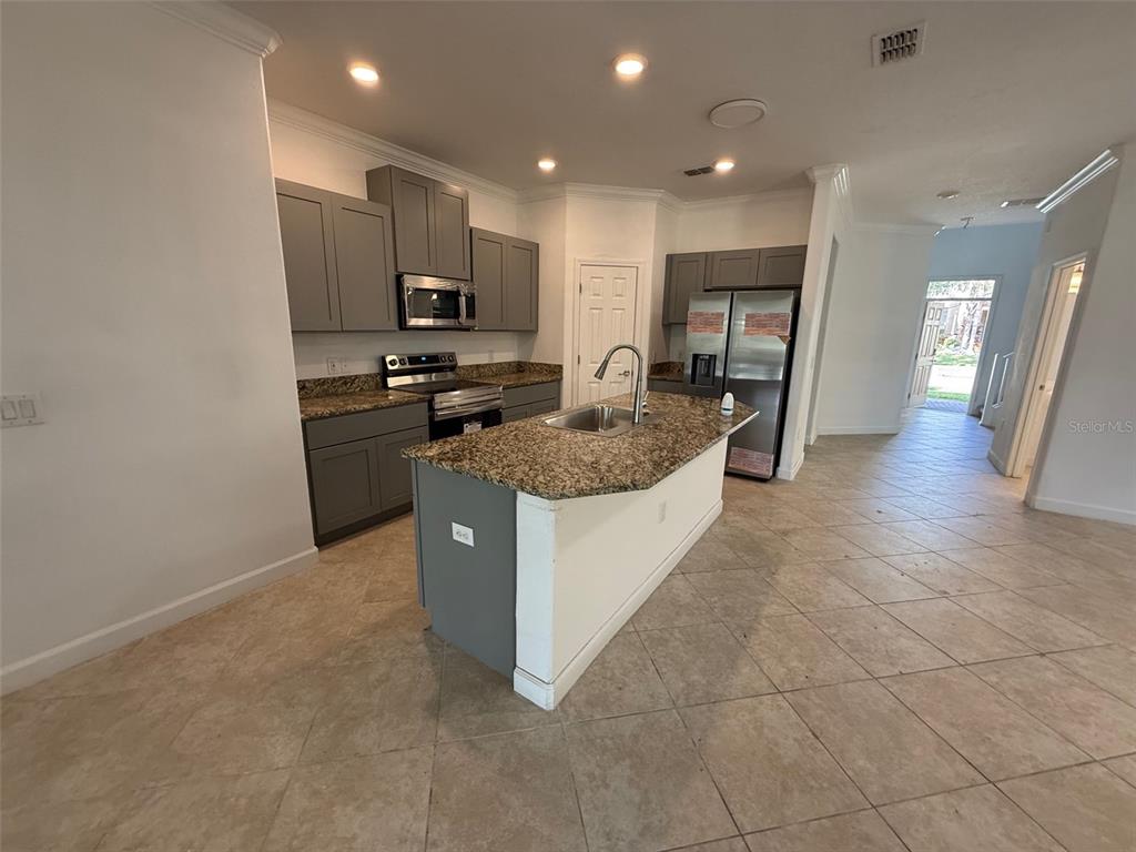 A kitchen features gray cabinets, granite countertops, a center island, and stainless steel appliances — 950 TERRA VISTA STREET, BRANDON, FL