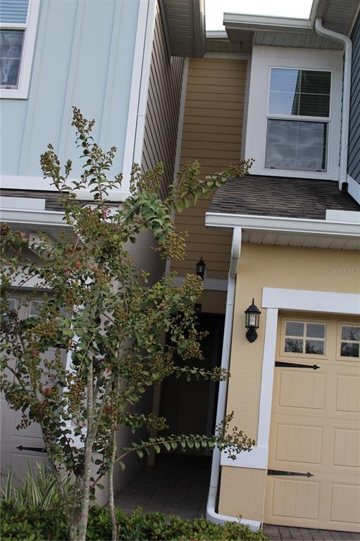 A view of the exterior of a multi-story townhouse with a garage and a small tree — 2193 SEDGE GRASS WAY, ORLANDO, FL