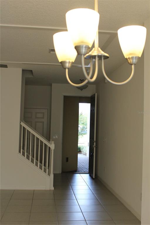 A tiled entryway features a staircase with a white railing and an open front door — 2193 SEDGE GRASS WAY, ORLANDO, FL
