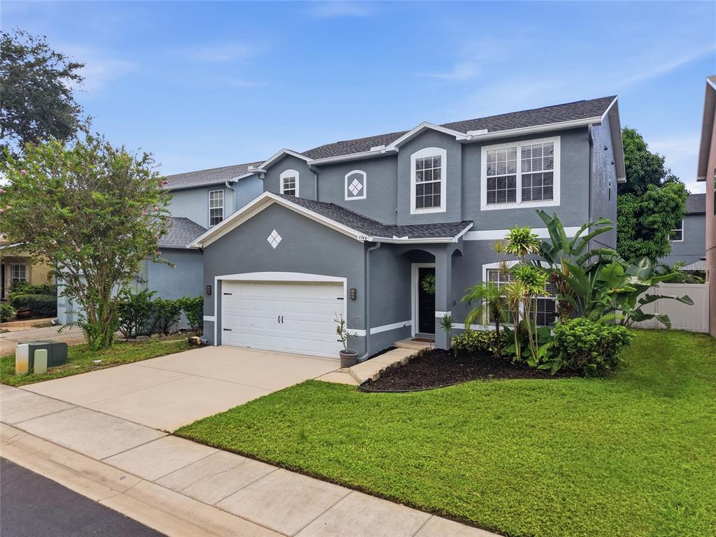 A two-story gray house with a white garage door, a front lawn, and landscaping — 7749 75TH STREET N, PINELLAS PARK, FL
