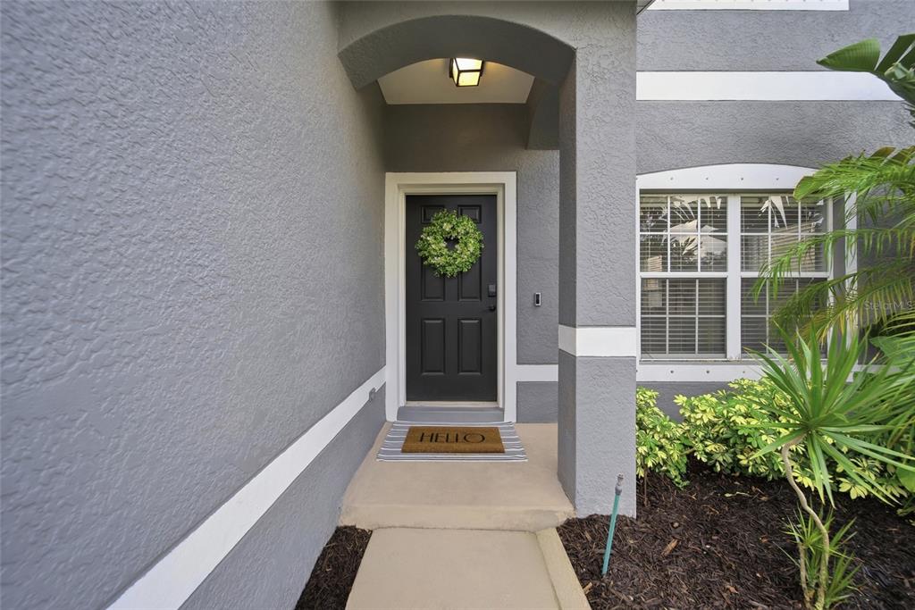 A gray house exterior features a black front door with a wreath and a welcome mat — 7749 75TH STREET N, PINELLAS PARK, FL
