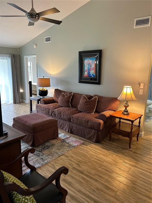 A living room features a patterned sofa, an ottoman, two lamps, and wood-look tile flooring — 13236 MOLITOR COURT, HUDSON, FL
