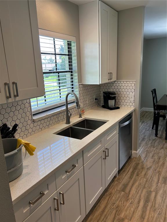 A kitchen features white cabinets, quartz countertops, a stainless steel sink, and hexagonal tile backsplash — 13236 MOLITOR COURT, HUDSON, FL
