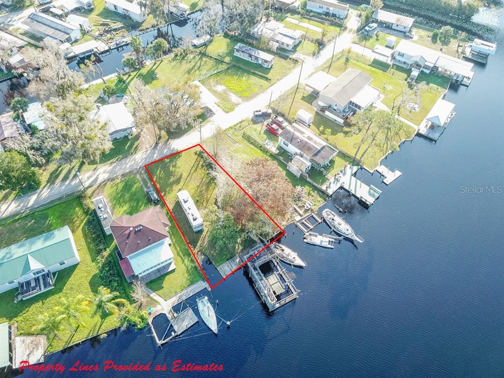 An aerial view shows a rectangular waterfront lot with a mobile home and boat dock — 144 MAGNOLIA TRAIL, SATSUMA, FL