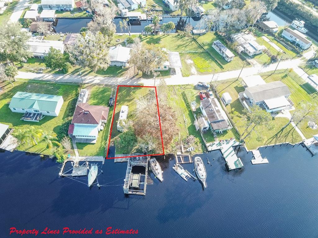 An aerial view shows a waterfront lot outlined in red with a dock and boat — 144 MAGNOLIA TRAIL, SATSUMA, FL