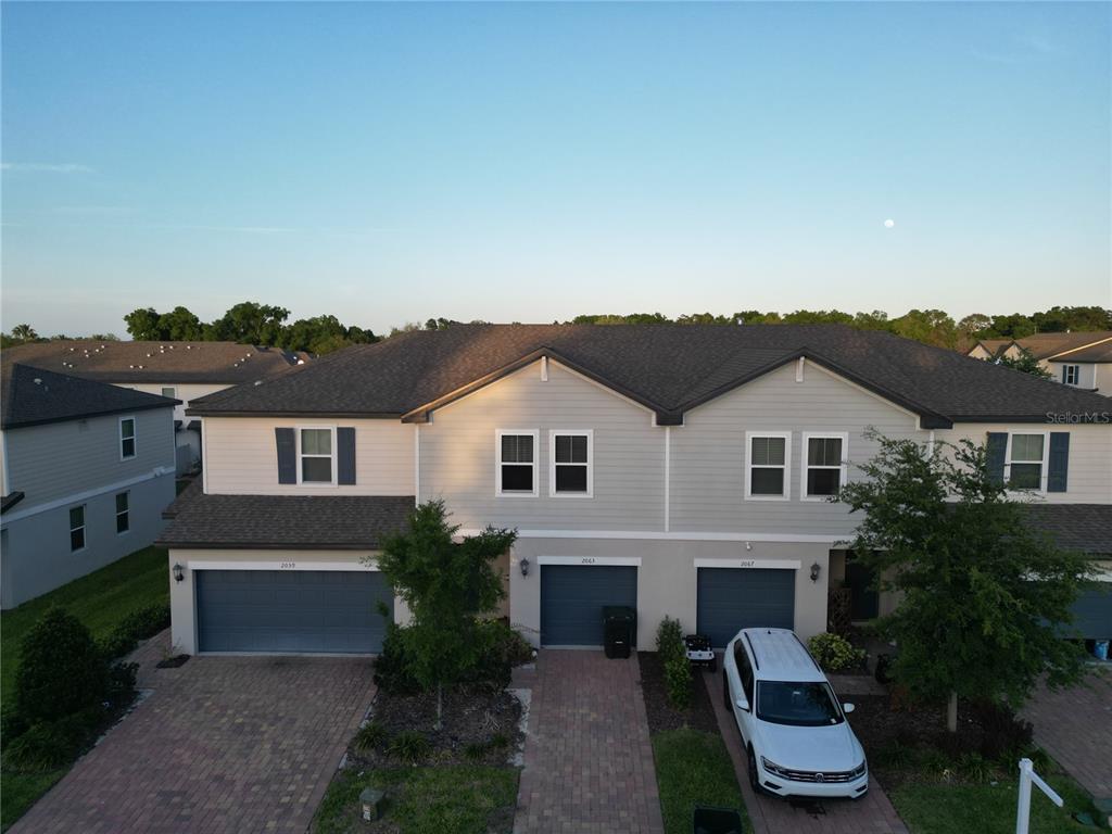 An aerial view of a multi-unit townhouse building with gray siding and paved driveways — 2063 HAREBELL LANE, OCOEE, FL