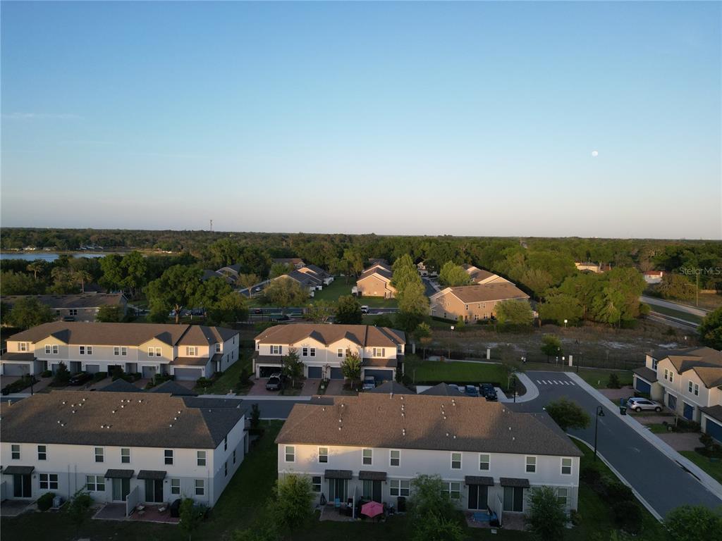 An aerial view shows multiple rows of suburban townhouses with paved streets and surrounding trees — 2063 HAREBELL LANE, OCOEE, FL
