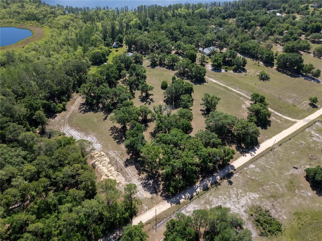 An aerial view shows a large, grassy, tree-dotted lot bordered by a dirt road — DR BAKER ROAD, GROVELAND, FL