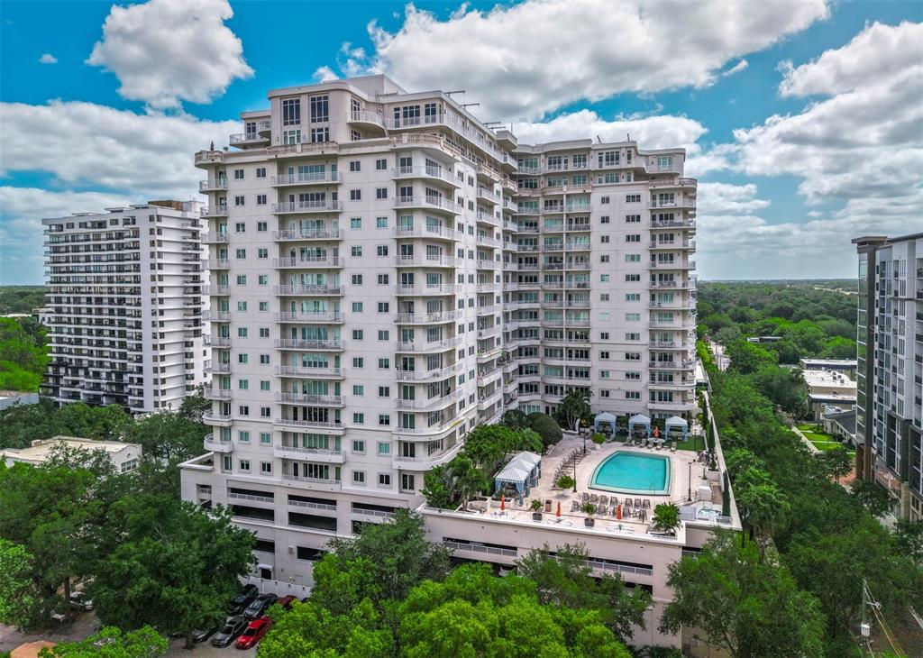 An exterior view of a tall white residential building with a pool and parking deck — 100 S EOLA DRIVE UNIT 1005, ORLANDO, FL
