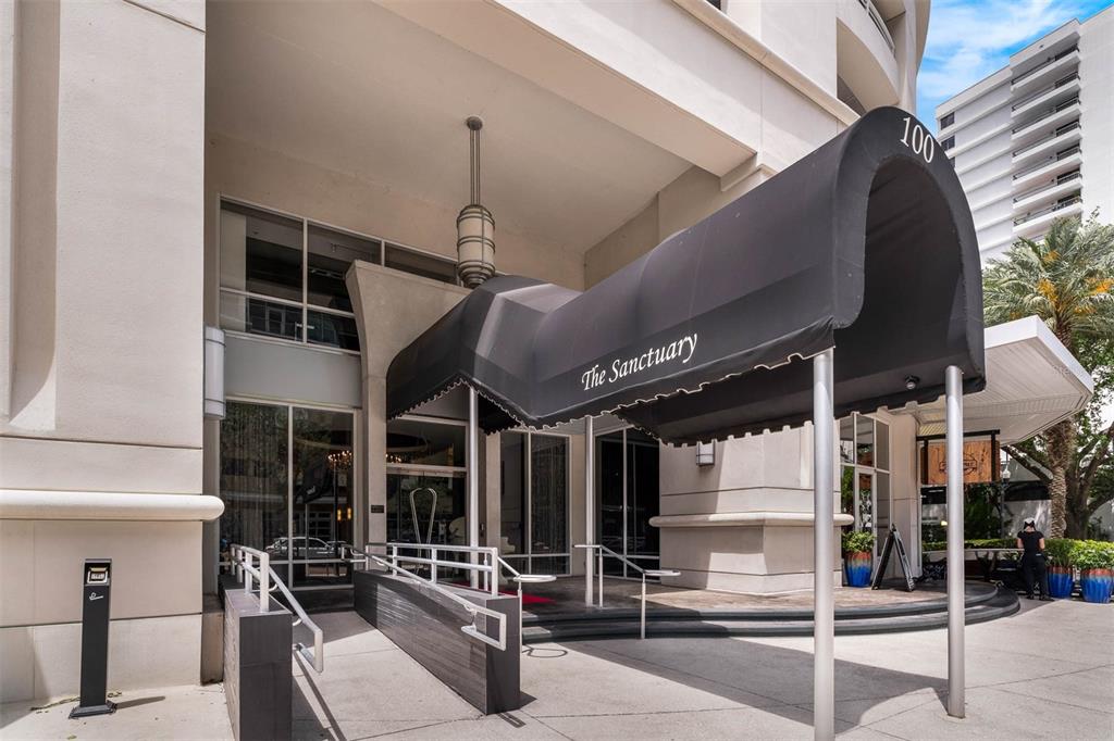 The exterior entrance of a building features a black awning labeled The Sanctuary — 100 S EOLA DRIVE UNIT 1005, ORLANDO, FL