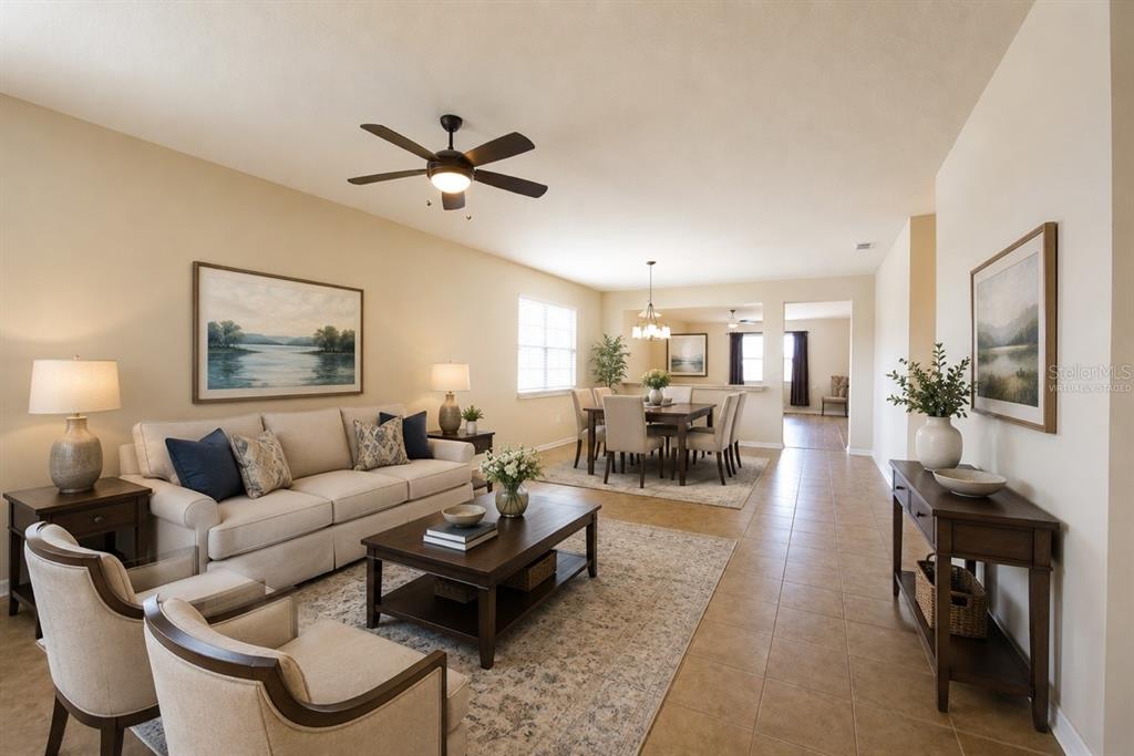 A living room and dining area with tile floors, neutral walls, and a ceiling fan — 10026 WEATHERS LOOP, CLERMONT, FL