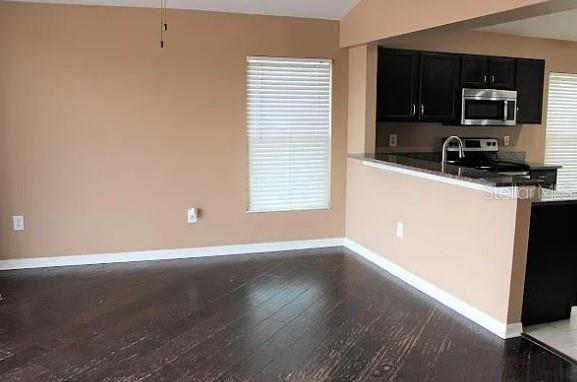 An open-concept dining area with dark wood floors connects to a kitchen with dark cabinets — 6414 OPEN PASTURE COURT, WESLEY CHAPEL, FL