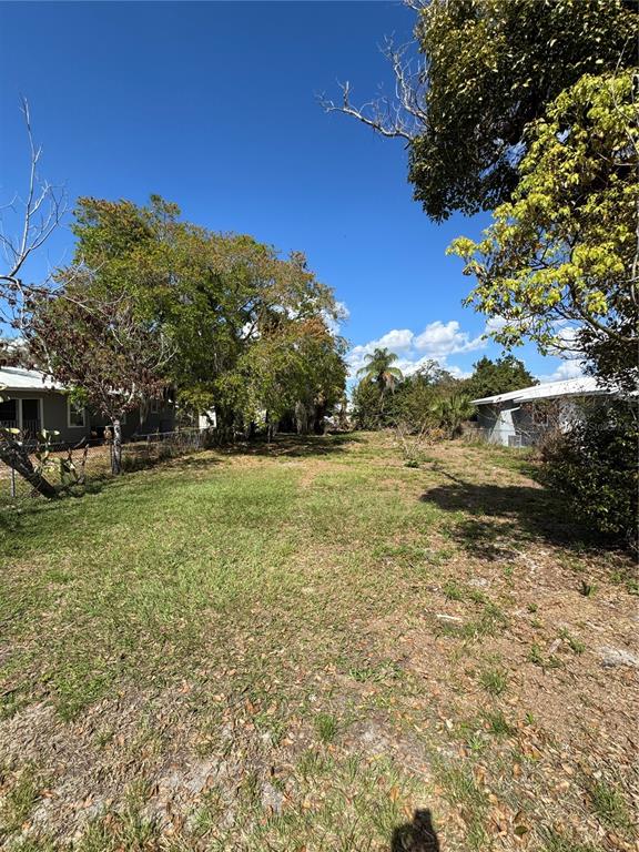 A grassy, vacant residential lot sits between two houses under a clear blue sky — 831 4TH STREET, WINTER HAVEN, FL
