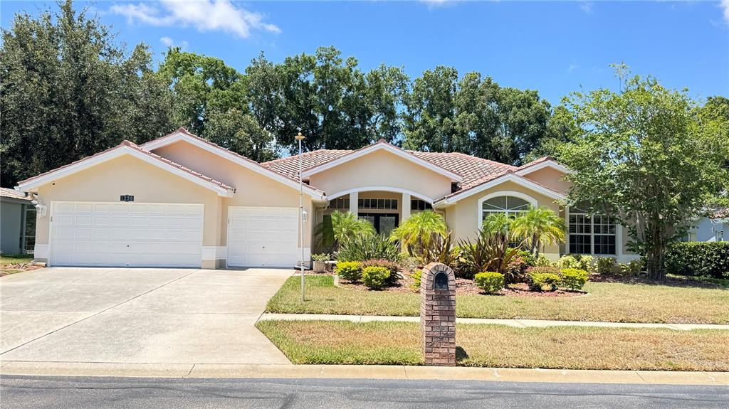 A single-story house with a beige exterior, tile roof, and a two-car garage — 1230 BERKSHIRE LANE, TARPON SPRINGS, FL