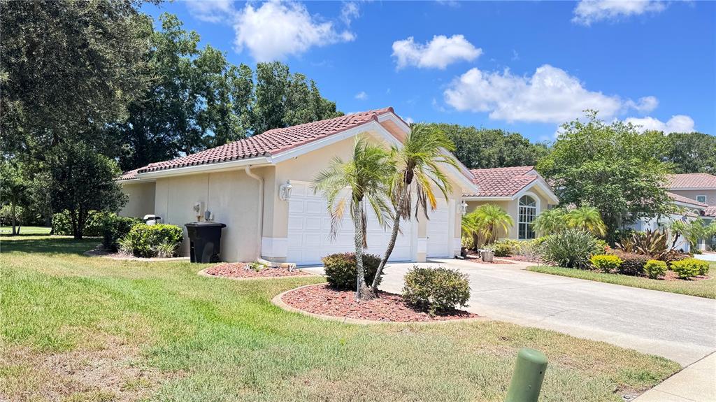 A single-story house with a tiled roof, two-car garage, and landscaped front yard — 1230 BERKSHIRE LANE, TARPON SPRINGS, FL