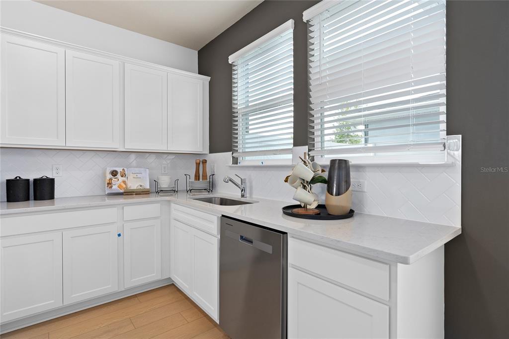 A kitchen features white cabinets, a stainless steel dishwasher, and a white herringbone backsplash — 1151 LEMONGRASS ALLEY, ORLANDO, FL