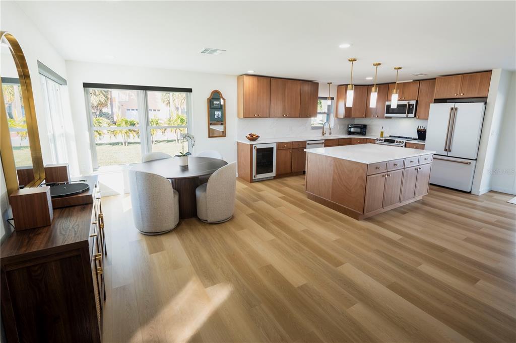A bright kitchen and dining area features wood cabinetry, a central island, and light flooring — 705 GULF BOULEVARD, BELLEAIR BEACH, FL