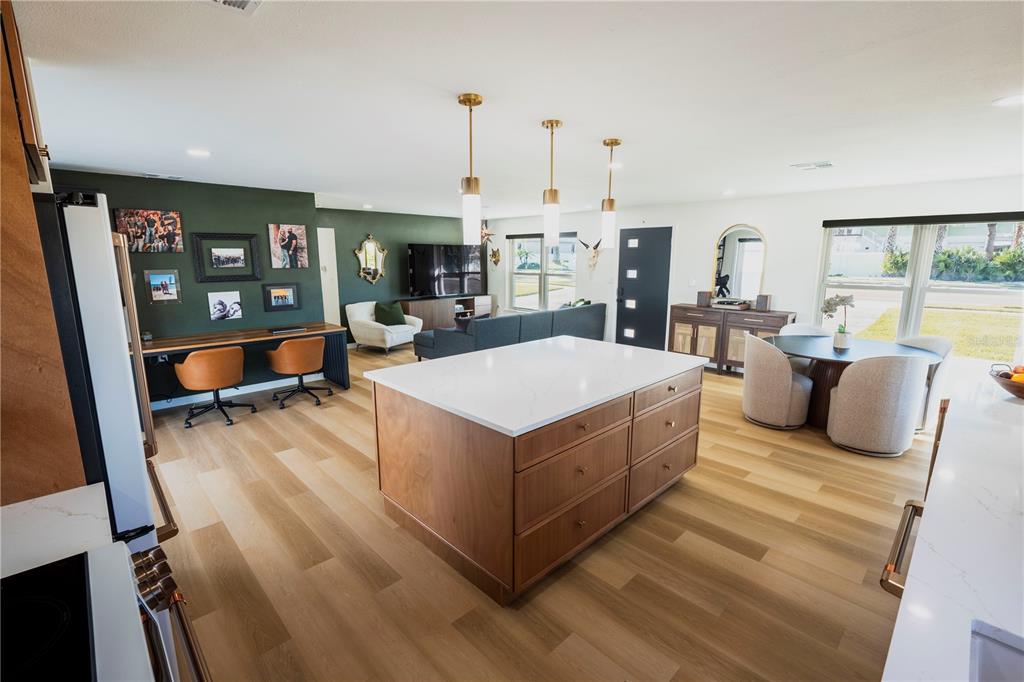 An open-concept kitchen and living area featuring a wood island, green accent wall, and desk — 705 GULF BOULEVARD, BELLEAIR BEACH, FL