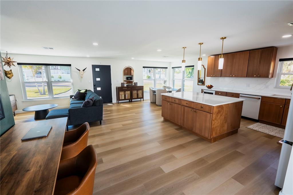 An open-concept living room and kitchen featuring wood flooring, a central island, and modern cabinetry — 705 GULF BOULEVARD, BELLEAIR BEACH, FL