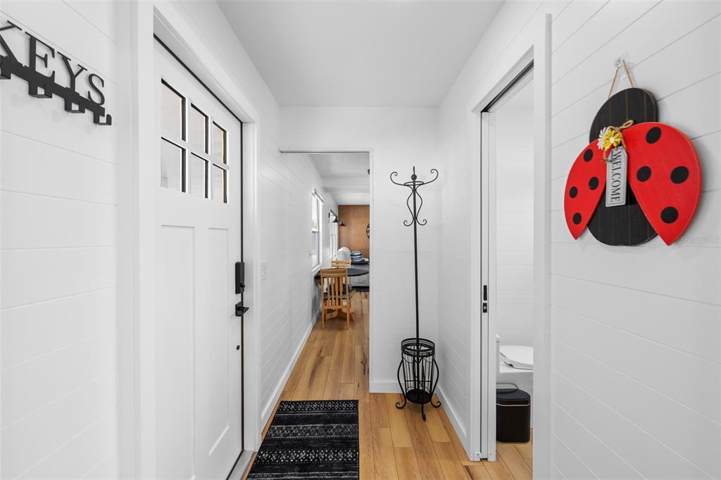 An entryway with white shiplap walls, a black door, and a ladybug welcome sign — 1109 45TH AVENUE E, ELLENTON, FL