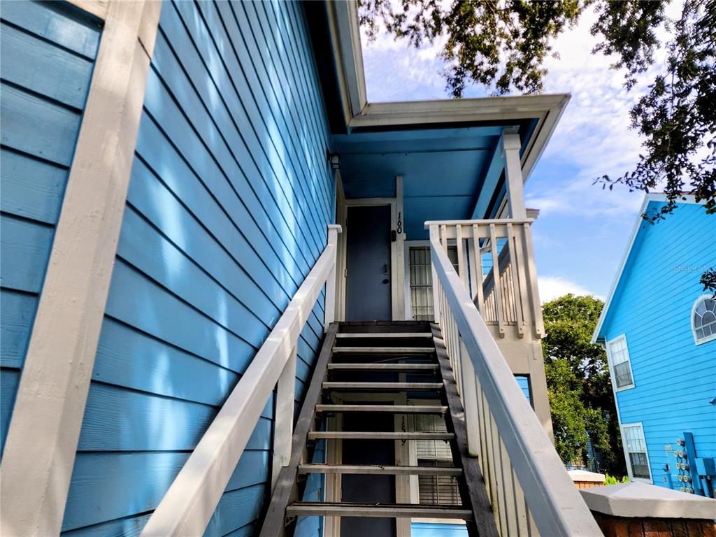 An exterior view of a blue building with an outdoor staircase leading to a doorway — 2723 N POINCIANA BOULEVARD UNIT 160, KISSIMMEE, FL
