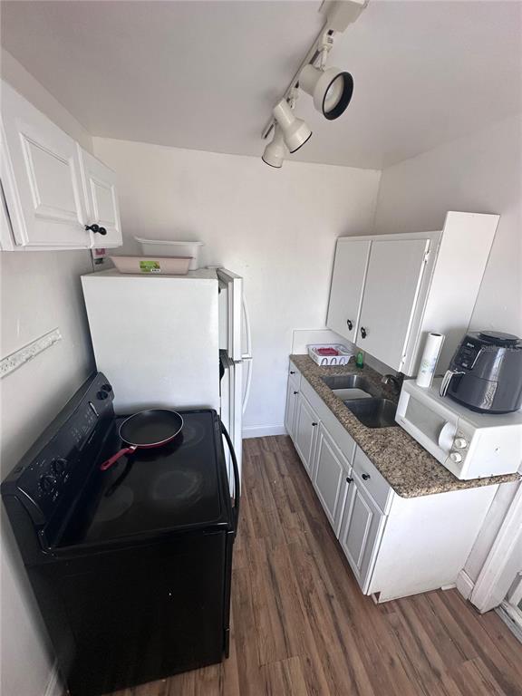 A small kitchen features white cabinets, a black stove, a refrigerator, and a granite countertop — 3000 KENILWORTH BOULEVARD, SEBRING, FL