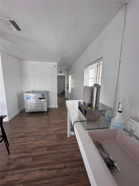 A commercial kitchen space features wood-look flooring, white walls, and a stainless steel prep station — 3000 KENILWORTH BOULEVARD, SEBRING, FL
