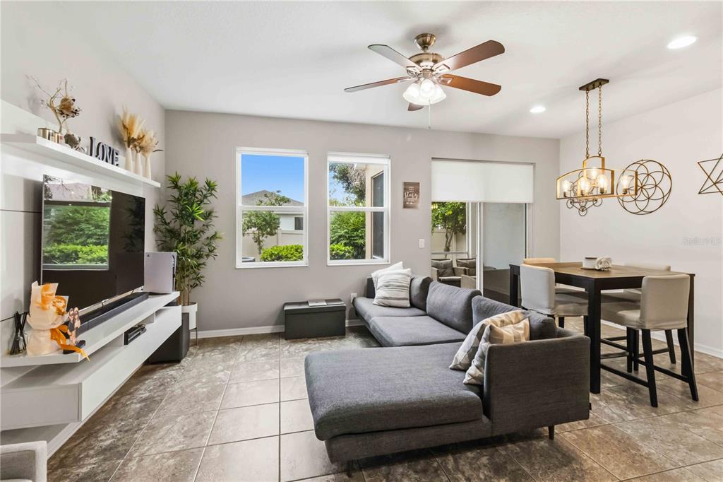 A living and dining area with tile floors, a gray sectional sofa, and a television — 10716 AVERY PARK DRIVE, RIVERVIEW, FL