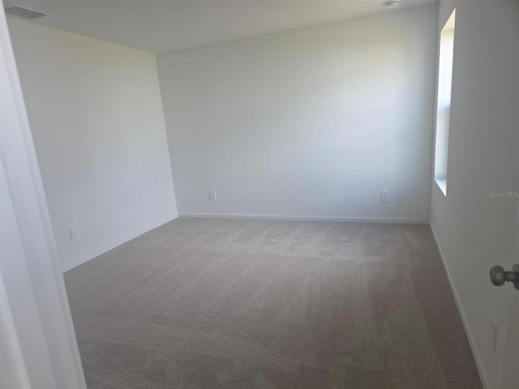 An empty bedroom features light-colored walls, neutral carpeting, and a single window — 3507 ROVER ROAD, EAGLE LAKE, FL