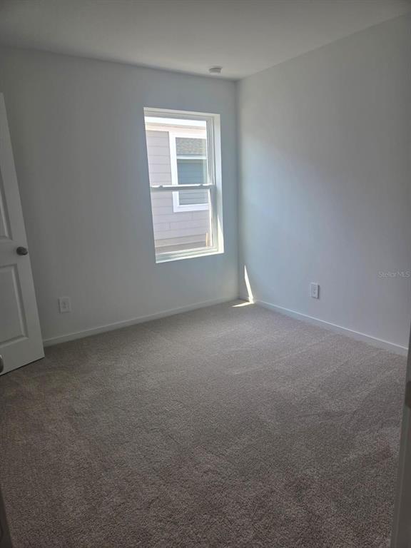 An empty bedroom features white walls, beige carpeting, and a single window — 3507 ROVER ROAD, EAGLE LAKE, FL