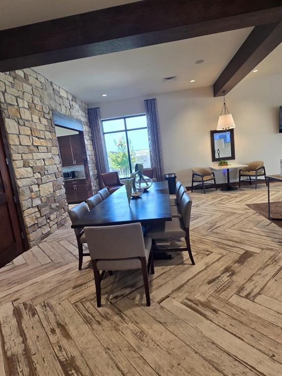 A dining area features a long wooden table, stone accent wall, and herringbone wood flooring — 3507 ROVER ROAD, EAGLE LAKE, FL