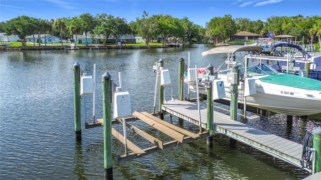 A boat lift and a docked pontoon boat sit in a canal near waterfront houses — 11025 W HARBOR WATCH LOOP UNIT 31, CRYSTAL RIVER, FL