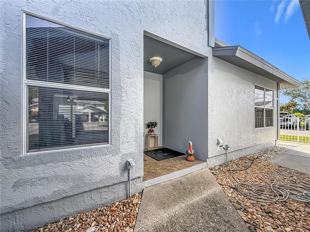 The exterior of a house features a recessed entryway, a concrete walkway, and gravel landscaping — 11025 W HARBOR WATCH LOOP UNIT 31, CRYSTAL RIVER, FL
