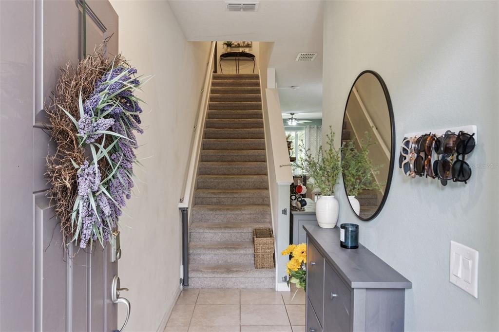 An entryway features a staircase with carpeted steps, a gray console table, and a wall mirror — 5329 SYLVESTER LOOP, TAMPA, FL